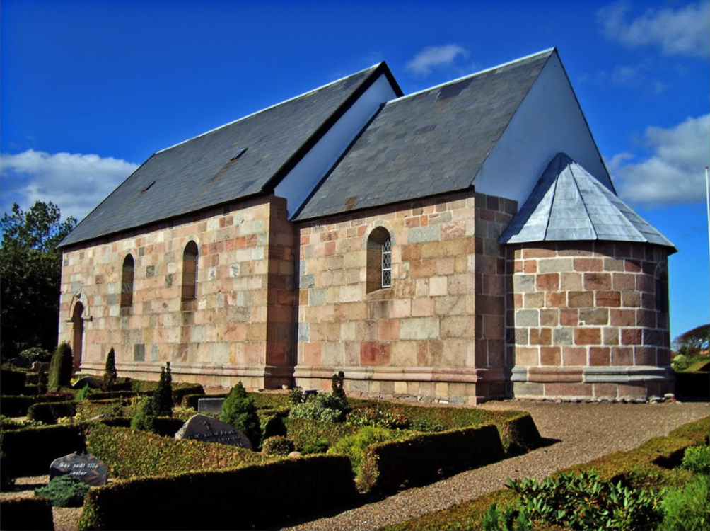 Foulum Kirke set fra sydøst med granitmure, skib, kor og apsis.